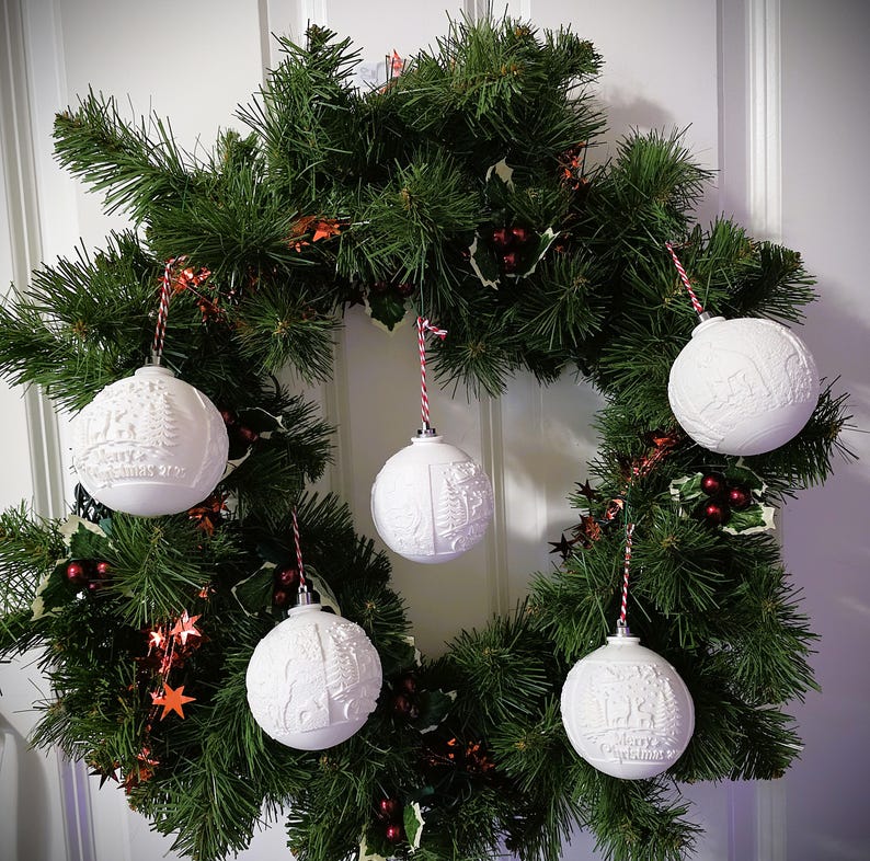 Set of custom white lithophane Christmas ornaments displayed on a festive wreath
